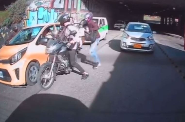 En cuestión de segundos, el delincuente logra arrebatarle un bolso a la pasajera y también le quita sus pertenencias al conductor.