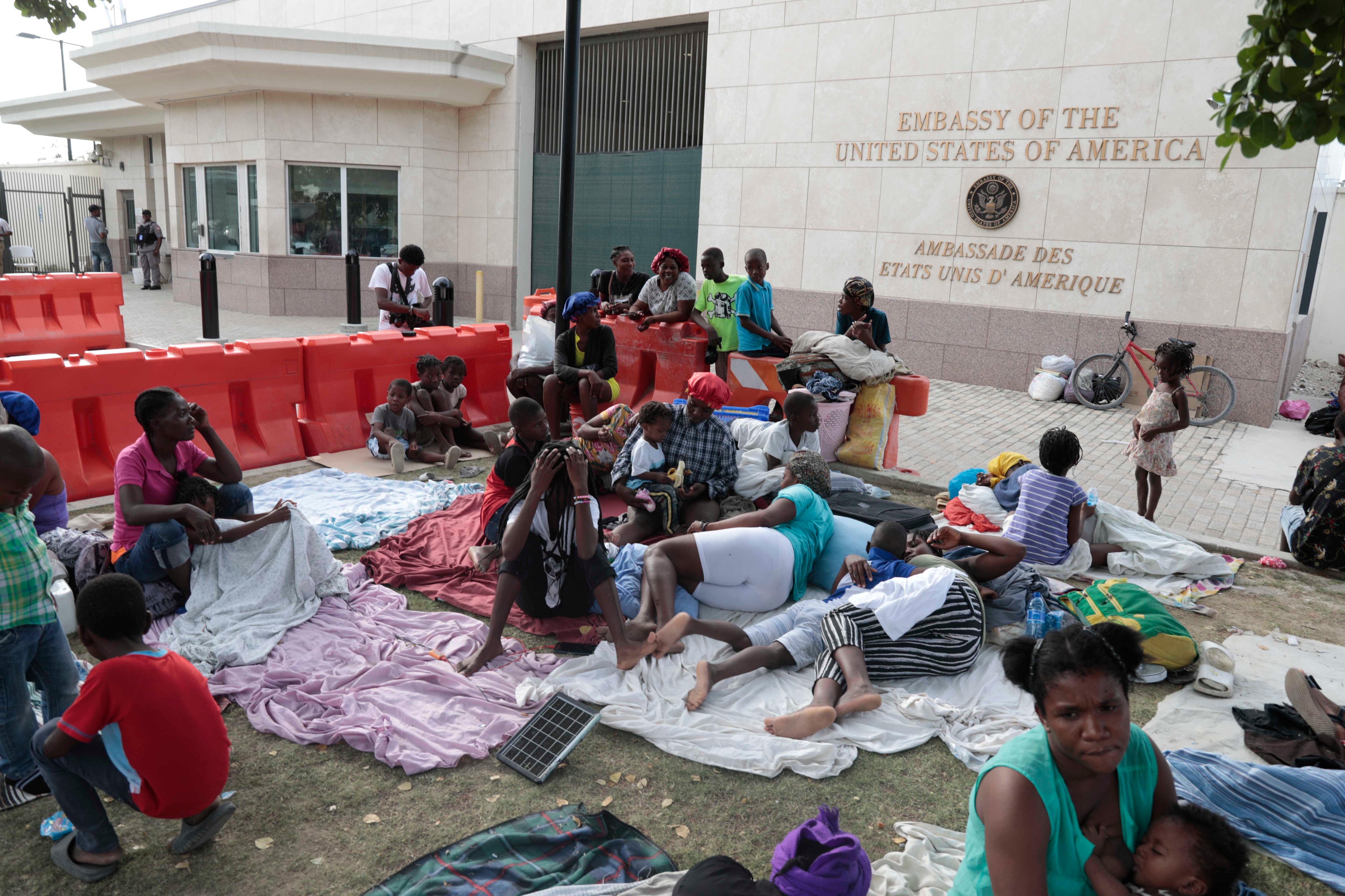 Personas desplazadas por bandas armadas de sus hogares en el barrio de Tabare descansan frente a la embajada de Estados Unidos en Puerto Príncipe, Haití
