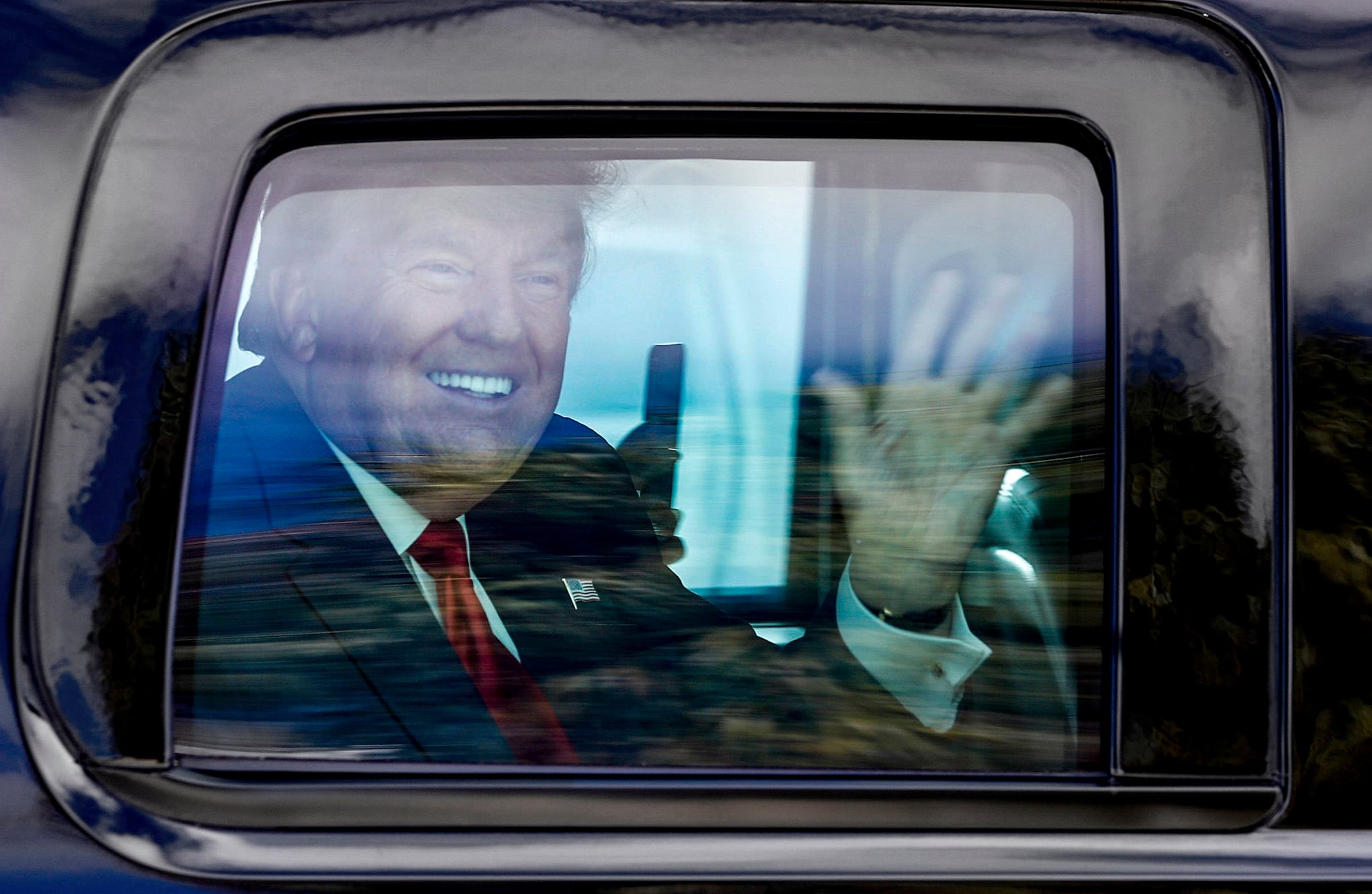 El expresidente Donald Trump saluda a sus seguidores mientras su caravana recorre West Palm Beach, Florida, de camino a su club Mar-a-Lago en Palm Beach después de llegar desde Washington a bordo del Air Force One el miércoles 20 de enero de 2021. (Damon Higgins / The Palm Beach Post vía AP)