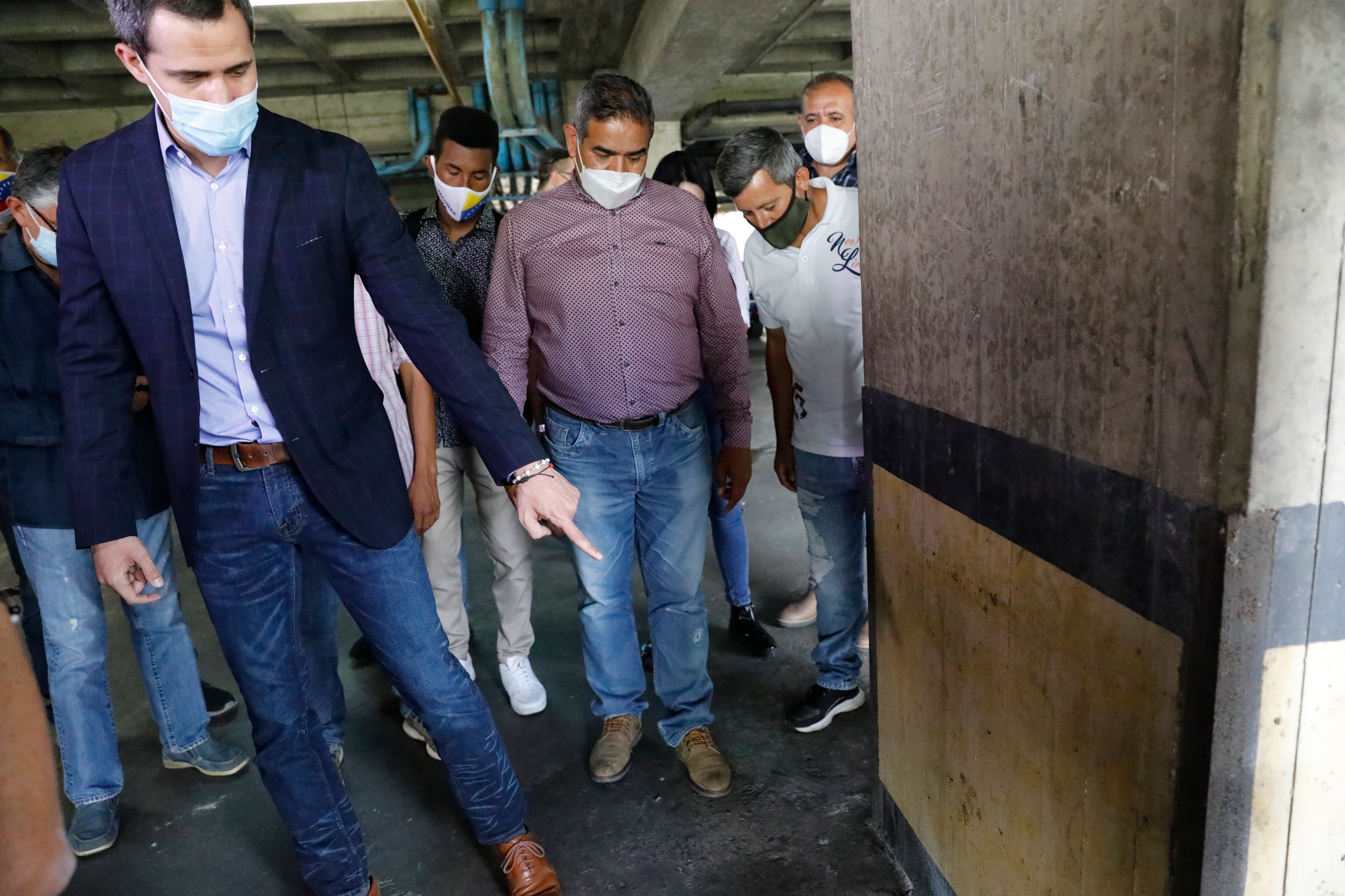 El líder de la oposición, Juan Guaidó, señala un lugar donde dice que las marcas en una columna son de disparos efectuados por las fuerzas de seguridad dentro del estacionamiento de su edificio residencial en Caracas, Venezuela, el lunes 12 de julio de 2021. Guaidó realizó una conferencia de prensa improvisada para decir que Las fuerzas de seguridad amenazaron a su conductor cuando llegaba a casa el lunes. (Foto AP / Ariana Cubillos)