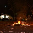Varios contenedores y canecas de basura arden en medio de la calle. Al fondo, la estación de trenes de Atocha.