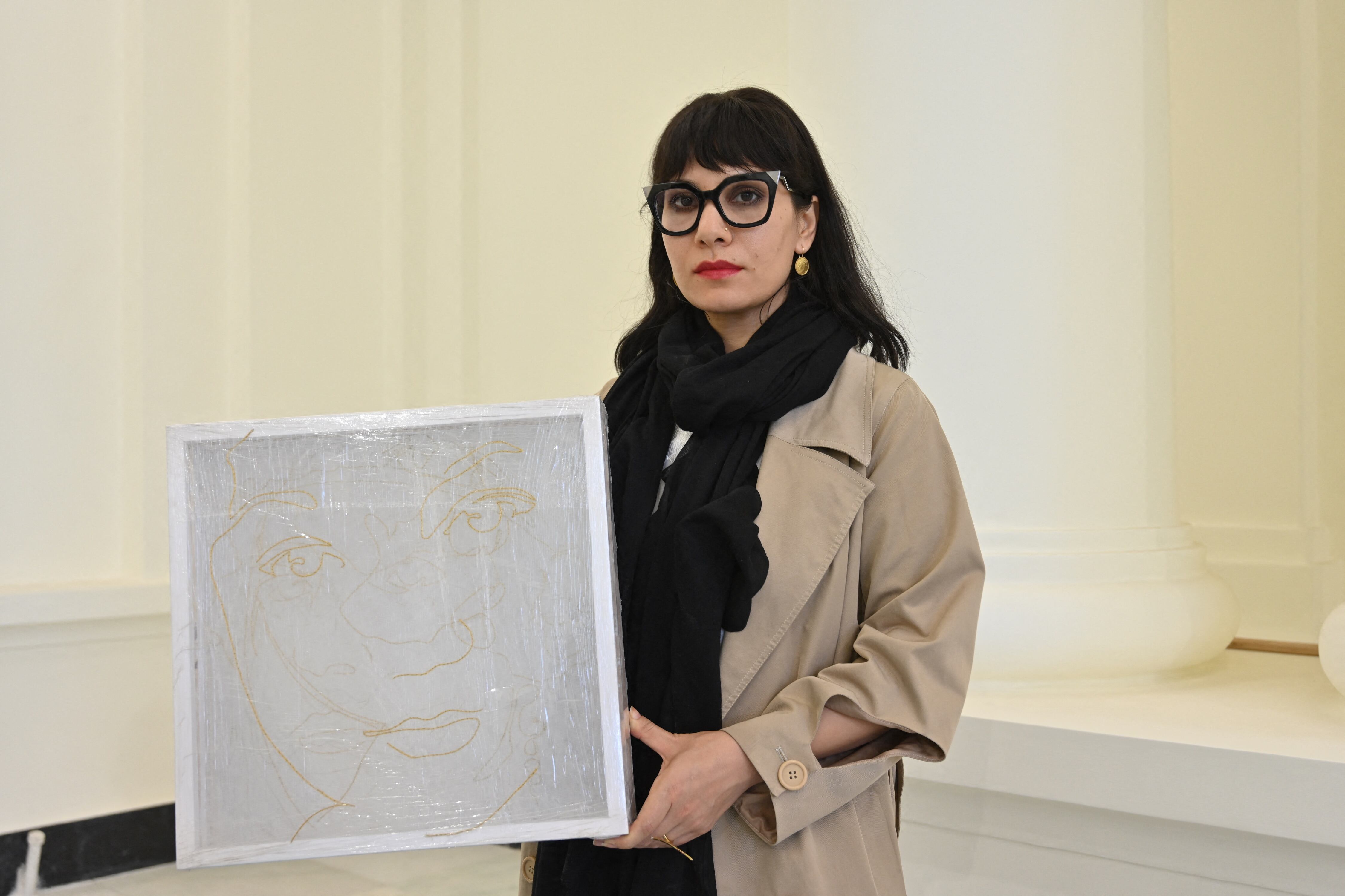 This picture taken in Kabul on June 24, 2021 shows Afghanistan visual artist and photographer Rada Akbar holding one of her artworks at the Darul Aman palace in Kabul. - Photographer Rada Akbar's striking self-portraits are a declaration of her independence and heritage -- but in Afghanistan that comes at a deadly risk. (Photo by ADEK BERRY / AFP) / TO GO WITH Afghanistan-conflict-women-Akbar,PROFILE by Anne Chaon
