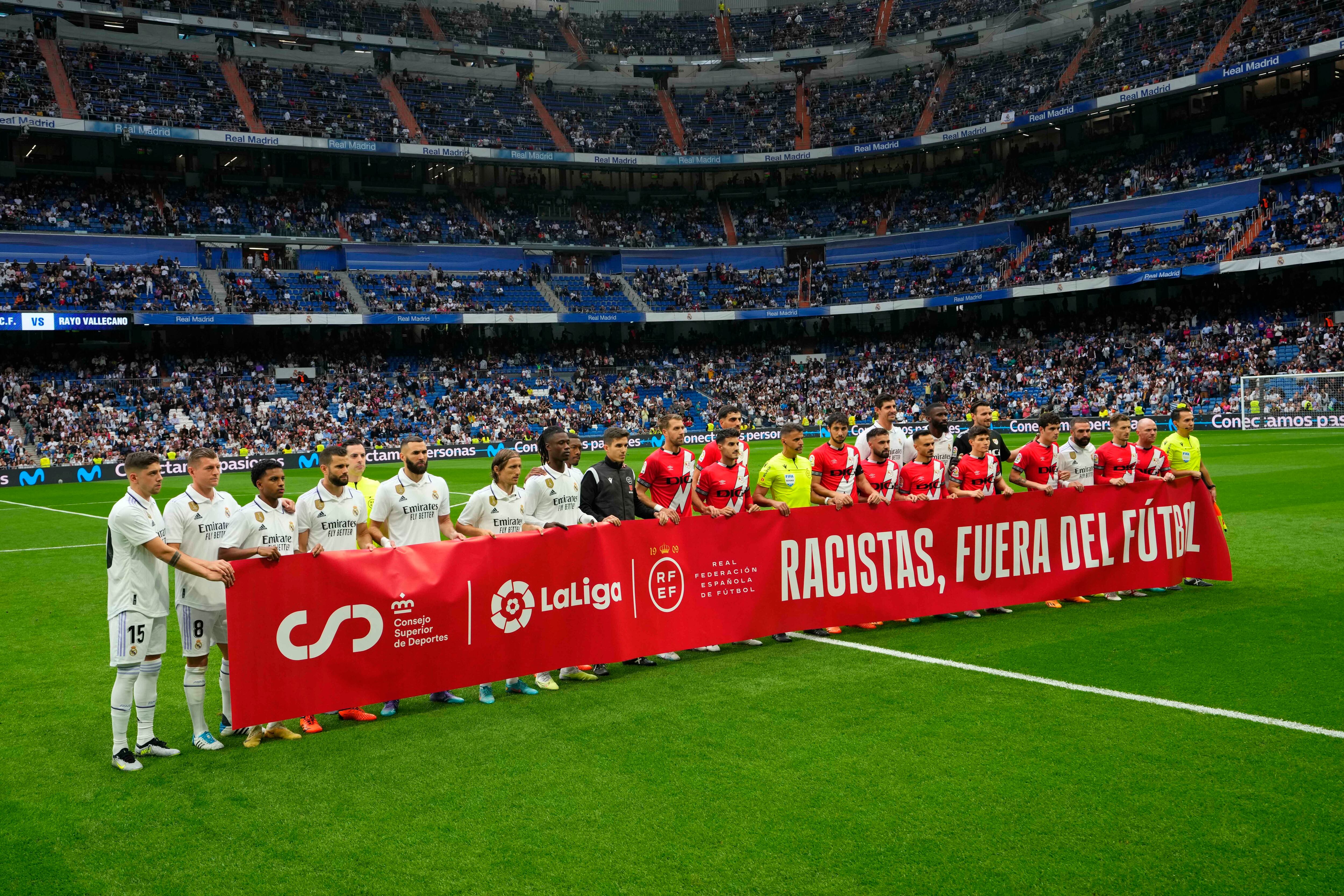 Players lift a banner reading 'Racists out of football' prior to a Spanish La Liga soccer match between Real Madrid and Rayo Vallecano at the Santiago Bernabeu stadium in Madrid, Spain, Wednesday, May 24, 2023. (AP Photo/Manu Fernandez)