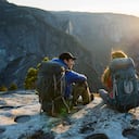 A couple sitting on a ledge while backpacking in Yosemite Valley.