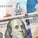 A macro image of a blue, two thousand Colombian peso bank note with a blue, crisp American one hundred dollar bill close up