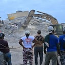 Voluntarios y residentes observan cómo una excavadora retira escombros de un edificio derrumbado en Caraballeda, estado de La Guaira, Venezuela, el 3 de julio de 2026
