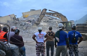 Voluntarios y residentes observan cómo una excavadora retira escombros de un edificio derrumbado en Caraballeda, estado de La Guaira, Venezuela, el 3 de julio de 2026