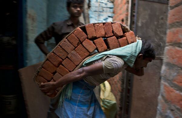 Este trabajador indio lleva gran cantidad de ladrillos sobre su espalda como parte de su trabajo en Nueva Delhi. (AP)