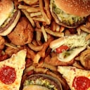 Concepto de comida rápida con restaurante frito grasiento para llevar como hamburguesa de aros de cebolla y perros calientes con papas fritas de pollo frito y pizza como símbolo de la tentación de la dieta que resulta en una nutrición poco saludable.