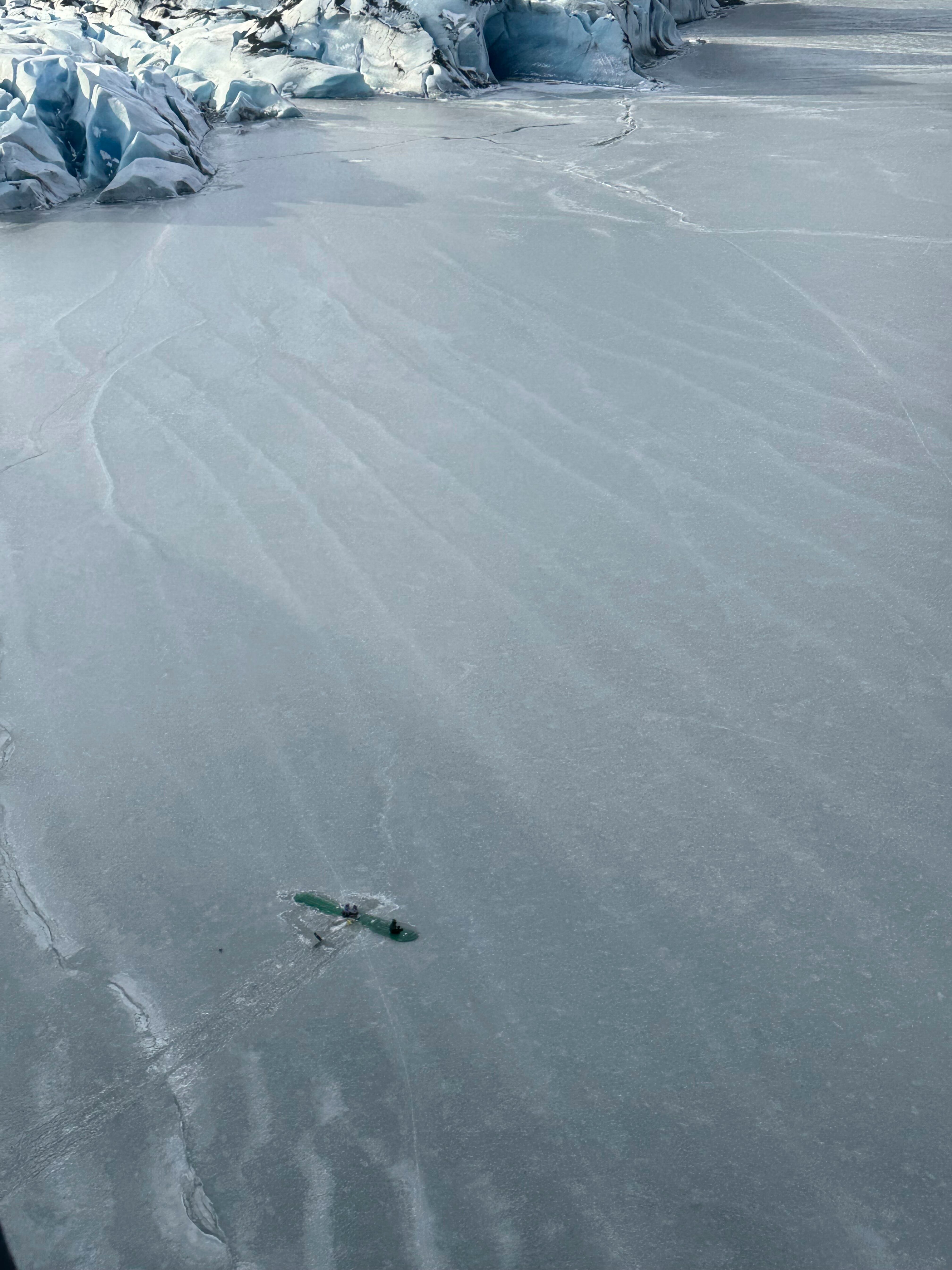 This photo provided Monday, March 24, 2025 by Dale Eicher shows an airplane partially submerged into the ice of Tustumena Lake near Soldotna, Alaska, with the three survivors standing on the plane's wing. (Dale Eicher via AP)