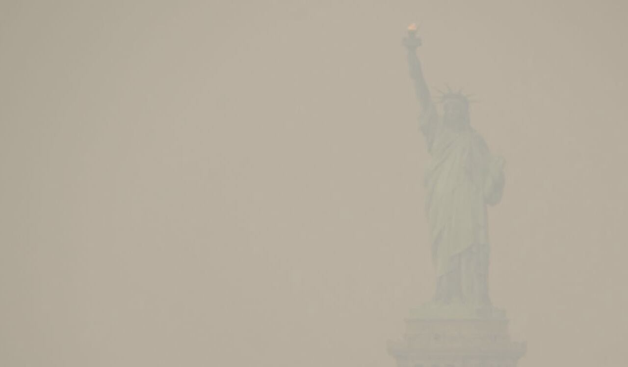 La Estatua de la Libertad se ve opaca tras el humo que tiene encima la ciudad