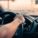 Mano del hombre conduciendo un coche en la carretera.
