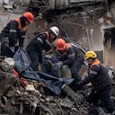 Los equipos de rescate transfieren el cuerpo de un hombre muerto en un ataque con misiles rusos en un edificio de apartamentos a una bolsa de plástico en la ciudad de Dnipro, en el sureste de Ucrania, el lunes 16 de enero de 2023. (AP Photo/Evgeniy Maloletka)