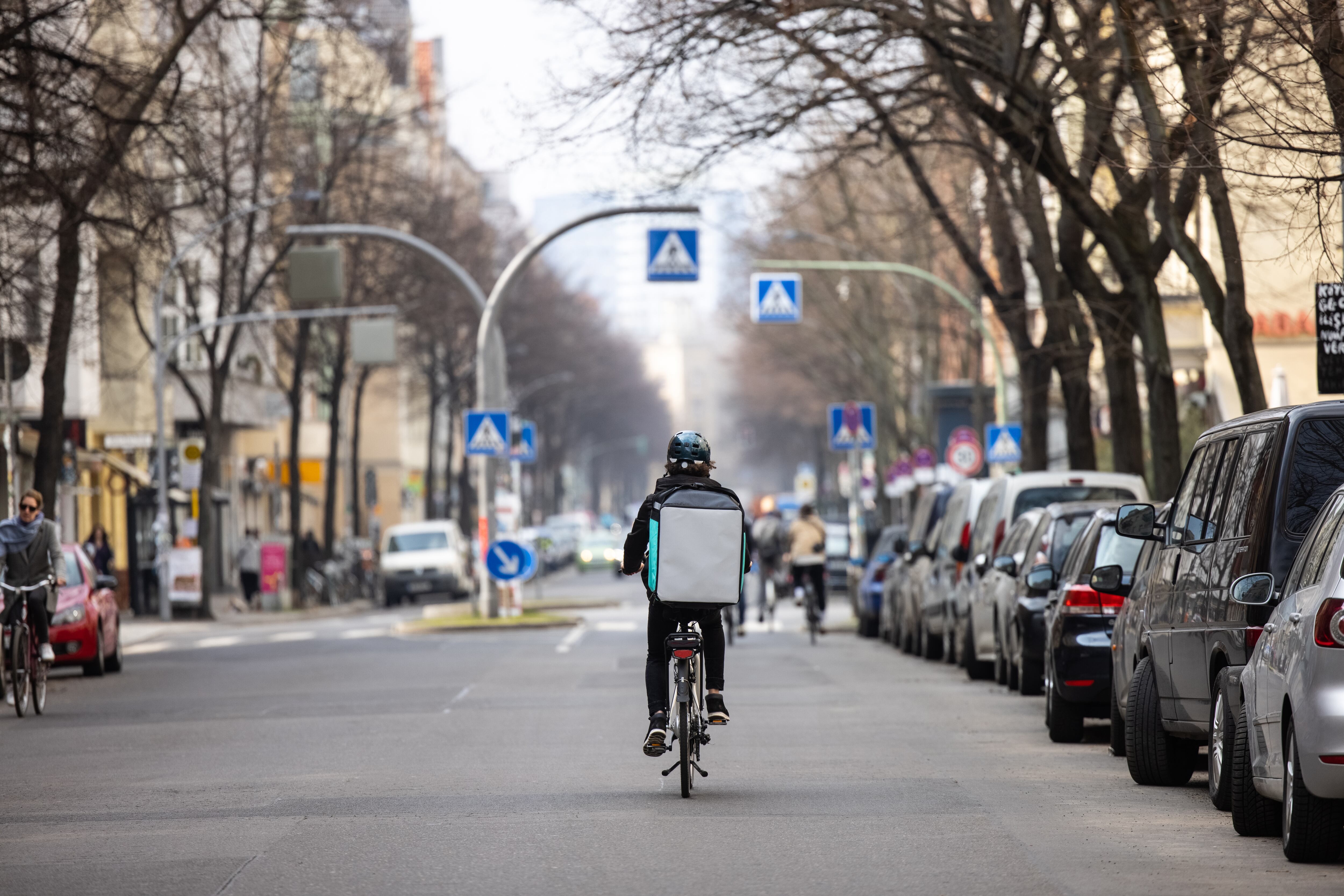 Food courier person with thermal backpack on city street