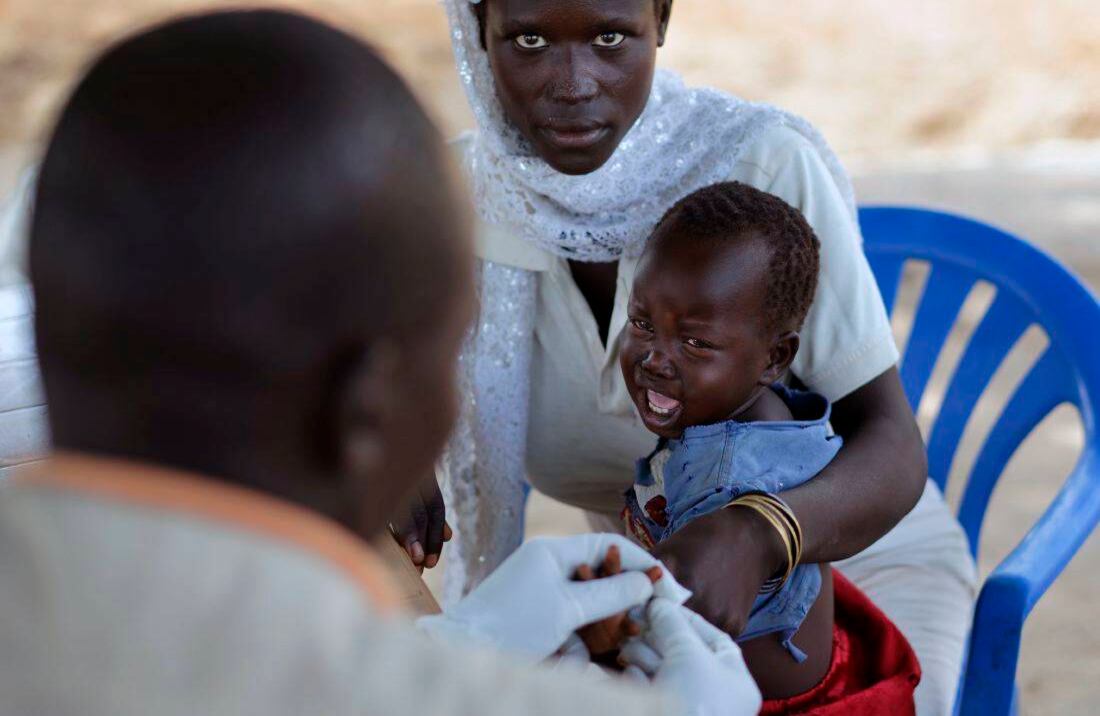 Samimu Bako llora mientras recibe un análisis de sangre de un médico, a la izquierda, como su madre Candiru Asia, en una clínica de salud móvil dirigida por el Comité Internacional de Rescate (Foto de AP / Ben Curtis)
