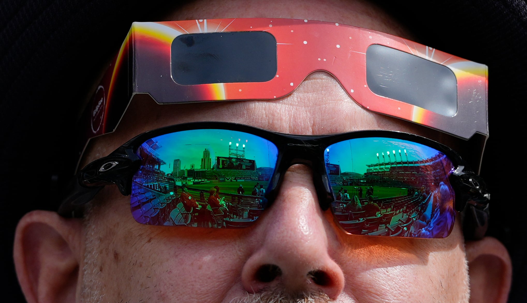 Un fanático usa gafas de sol, con vidrio de seguridad para eclipses listo, mientras la luna cubre parcialmente el sol durante un eclipse solar total en Progressive Field en Cleveland el lunes 8 de abril de 2024