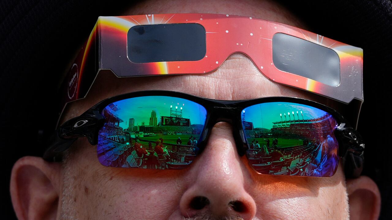 Un fanático usa gafas de sol, con vidrio de seguridad para eclipses listo, mientras la luna cubre parcialmente el sol durante un eclipse solar total en Progressive Field en Cleveland el lunes 8 de abril de 2024