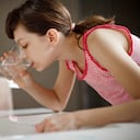 Teenage girl rinsing her mouth with glass of water