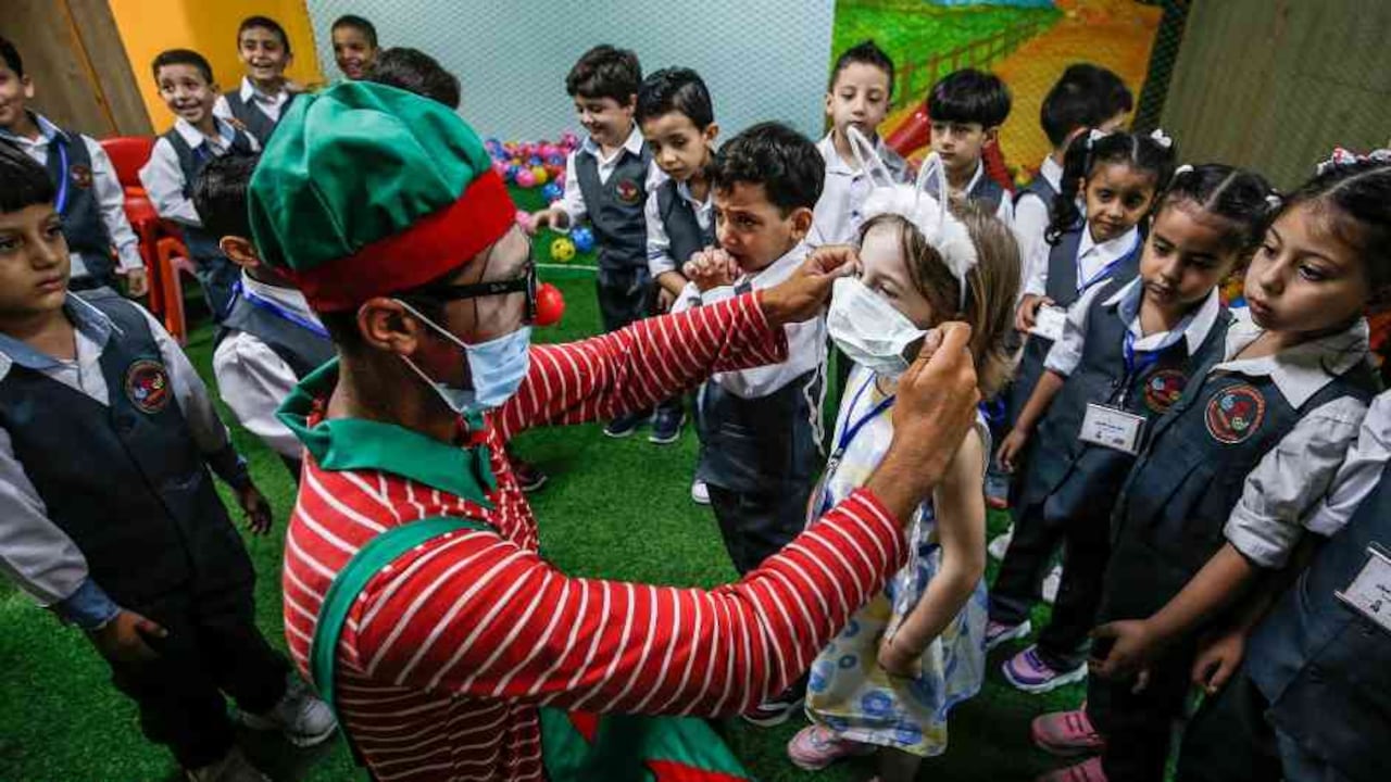 Personal educativo explica a los niños el uso del tapabocas.