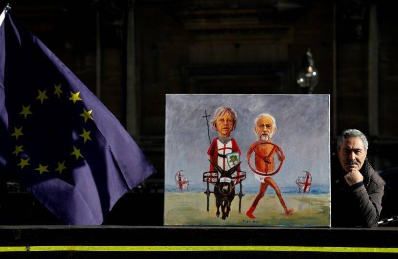 El artista de sátira política Kaya Mar posa con una obra de arte que representa al líder opositor del Partido Laborista, Jeremy Corbyn (R), y la primera ministra británica, Theresa May.  Mientras tanto activistas contra el Brexit se manifiestaban fuera de las Casas del Parlamento en el centro de Londres el 14 de febrero de 2019. FOTO: Adrian DENNIS / AFP