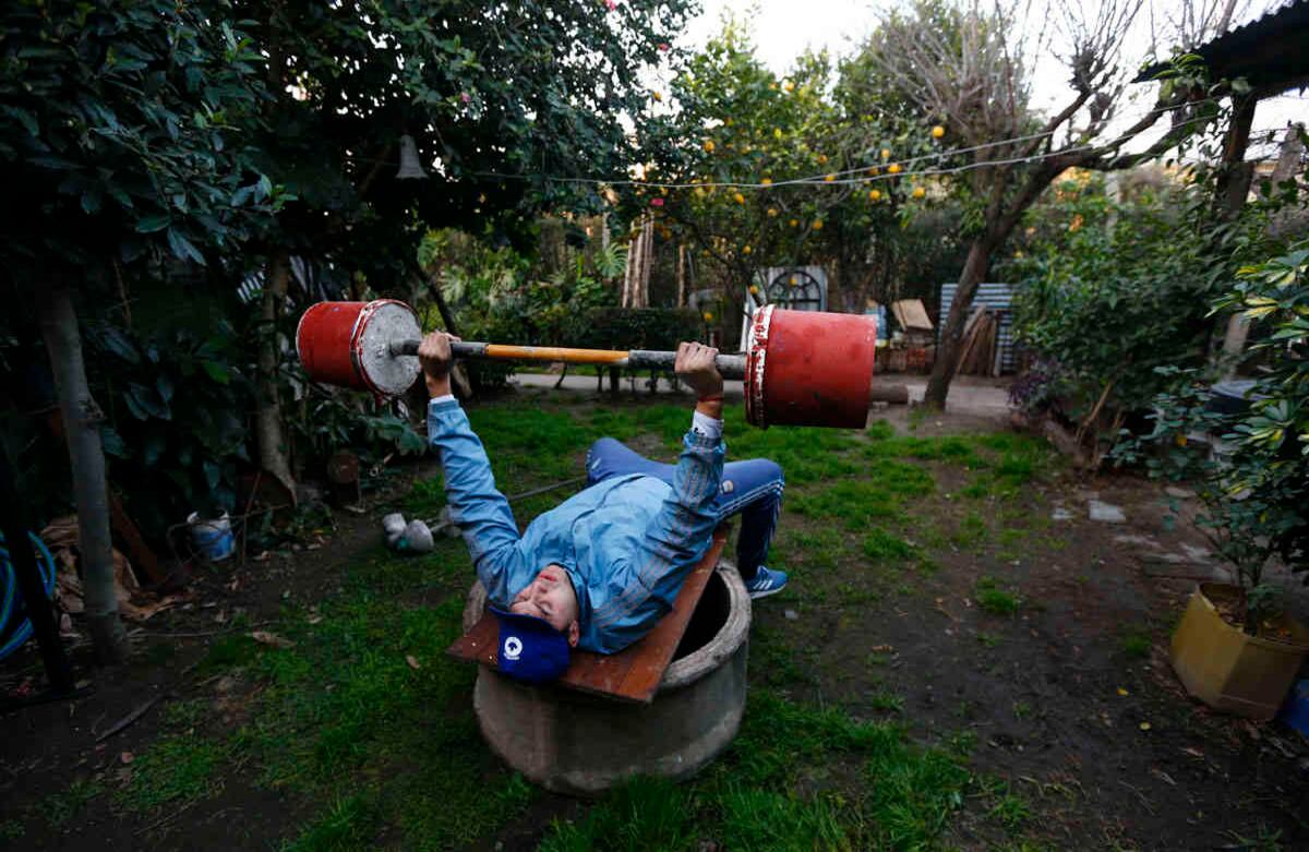Yamil Peralta levanta pesas hechas de cemento en el patio trasero de su casa, en José C. Paz, a las afueras de Buenos Aires, Argentina. En medio de la cuarentena contra la covid-19 el boxeador profesional encontró trabajo en una empresa de basura y adaptó su hogar para continuar entrenando con la esperanza de clasificarse para los olímpicos de Tokio 2021. Foto: Marcos Brindicci / AP