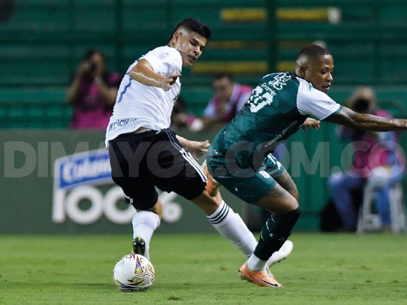 Jorge Arias y Jhon Vásquez disputan un balón sobre la banda derecha.