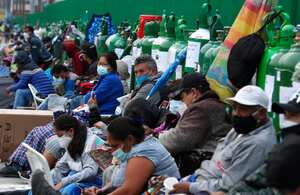 FILE - In this Feb. 22, 2021, file photo, people sit by their empty oxygen cylinders waiting for a refill shop to open in the San Juan de Lurigancho neighborhood of Lima, Peru. A crisis over the supply of medical oxygen for coronavirus patients has struck in Africa and Latin America, where warnings went unheeded at the start of the pandemic and doctors say the shortage has led to unnecessary deaths. (AP Photo/Martin Mejia, File)