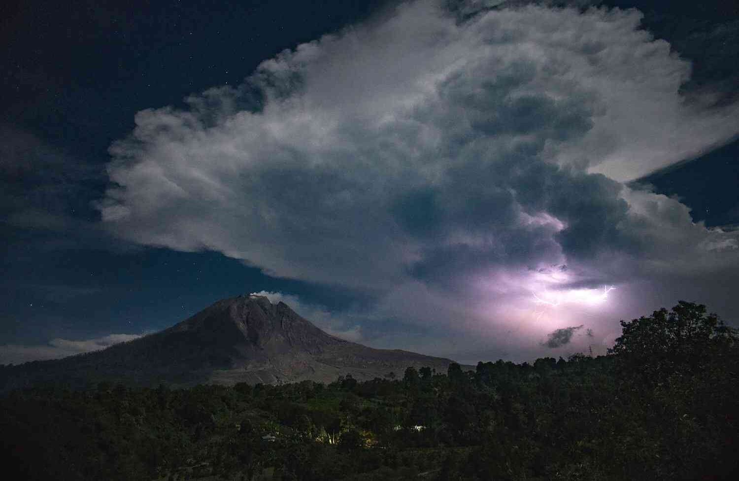 Esta foto tomada el 28 de abril de 2018 muestra luces y truenos sobre el volcán Monte Sinabung en Karo.  Sinabung volvió a la vida en 2010 por primera vez en 400 años, después de otro período de inactividad estalló una vez más en 2013, y se ha mantenido muy activo desde entonces. / AFP PHOTO / Lana Priatna