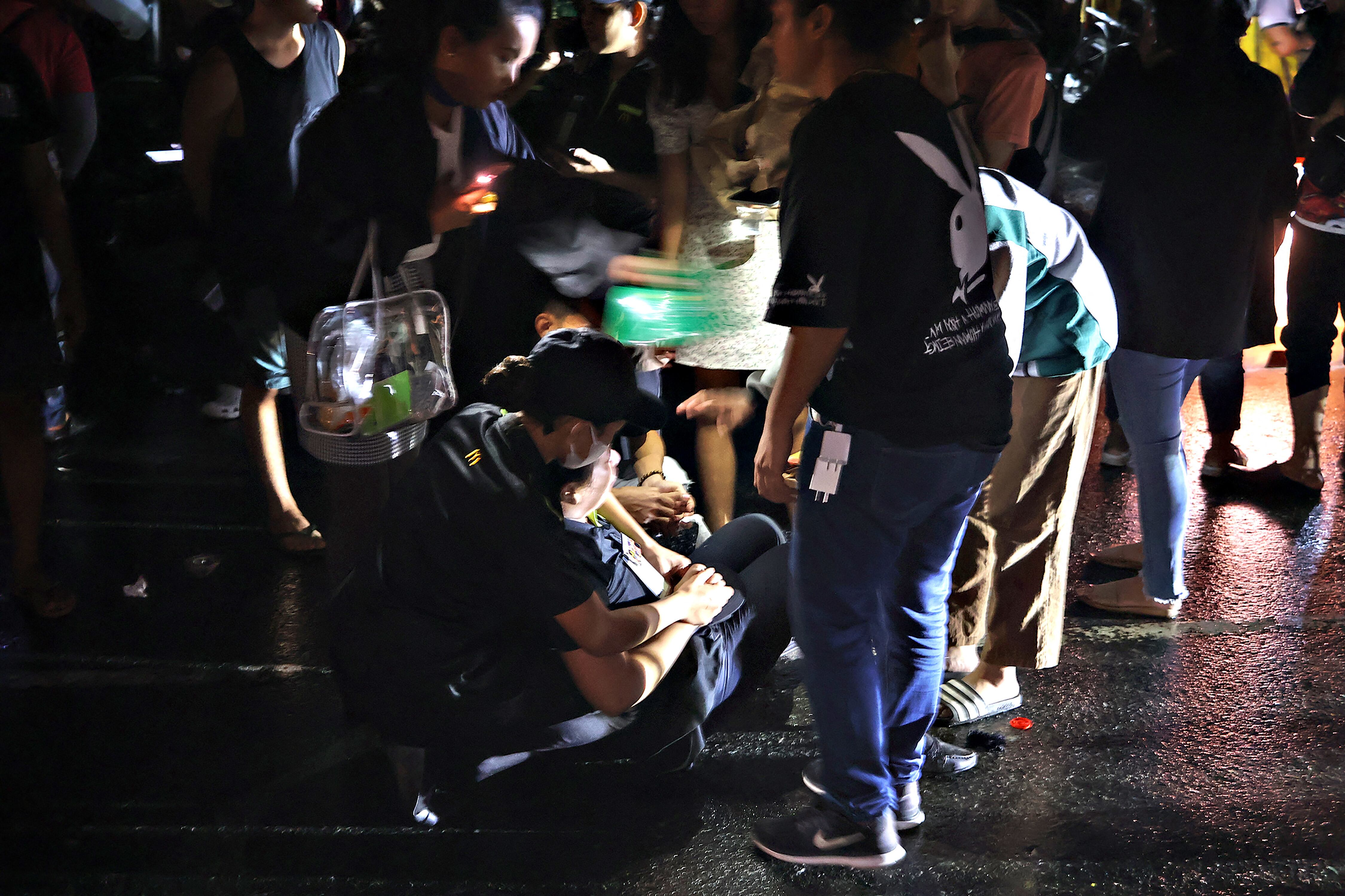 La gente ayuda a una mujer que se desmayó en una calle después de que un terremoto de 7,6 sacudiera la ciudad de Butuan