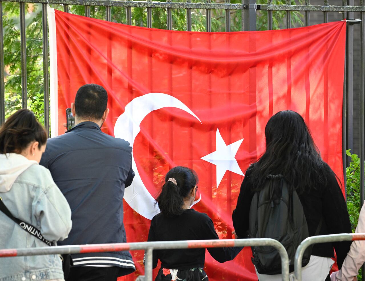 Los votantes turcos pasan una bandera turca mientras se dirigen al colegio electoral en el consulado turco en Berlín el 9 de mayo de 2023. Hay aproximadamente 1,5 millones de votantes turcos registrados que viven en Alemania, la diáspora más grande que participa en las elecciones más importantes de Turquía en décadas. . (Photo by Tobias SCHWARZ / AFP) / TO GO WITH AFP STORY BY FEMKE COLBORNE