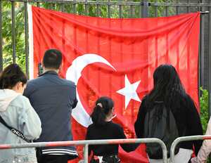 Los votantes turcos pasan una bandera turca mientras se dirigen al colegio electoral en el consulado turco en Berlín el 9 de mayo de 2023. Hay aproximadamente 1,5 millones de votantes turcos registrados que viven en Alemania, la diáspora más grande que participa en las elecciones más importantes de Turquía en décadas. . (Photo by Tobias SCHWARZ / AFP) / TO GO WITH AFP STORY BY FEMKE COLBORNE