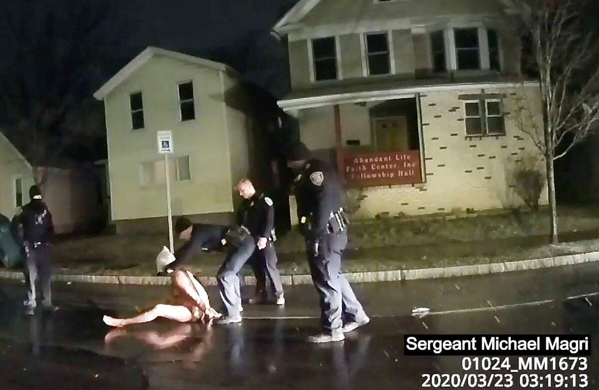 En esta imagen, tomada del video de la cámara del cuerpo de un policía, se ve como un oficial de policía de Rochester pone una capucha sobre la cabeza de Daniel Prude, el 23 de marzo de 2020, en Rochester, Nueva York. Prude, un hombre negro que había corrido desnudo por las calles del oeste de la ciudad de Nueva York murió asfixiado después de que los policías le cubrieran la cabeza con una capucha y luego presionaran su rostro contra el pavimento durante dos minutos, según un video publicado el 2 de septiembre por su familia. Prude murió el 30 de marzo después de que le quitaron el soporte vital, siete días después del encuentro con la policía en Rochester. Foto: Policía de Rochester / Roth LLP vía AP