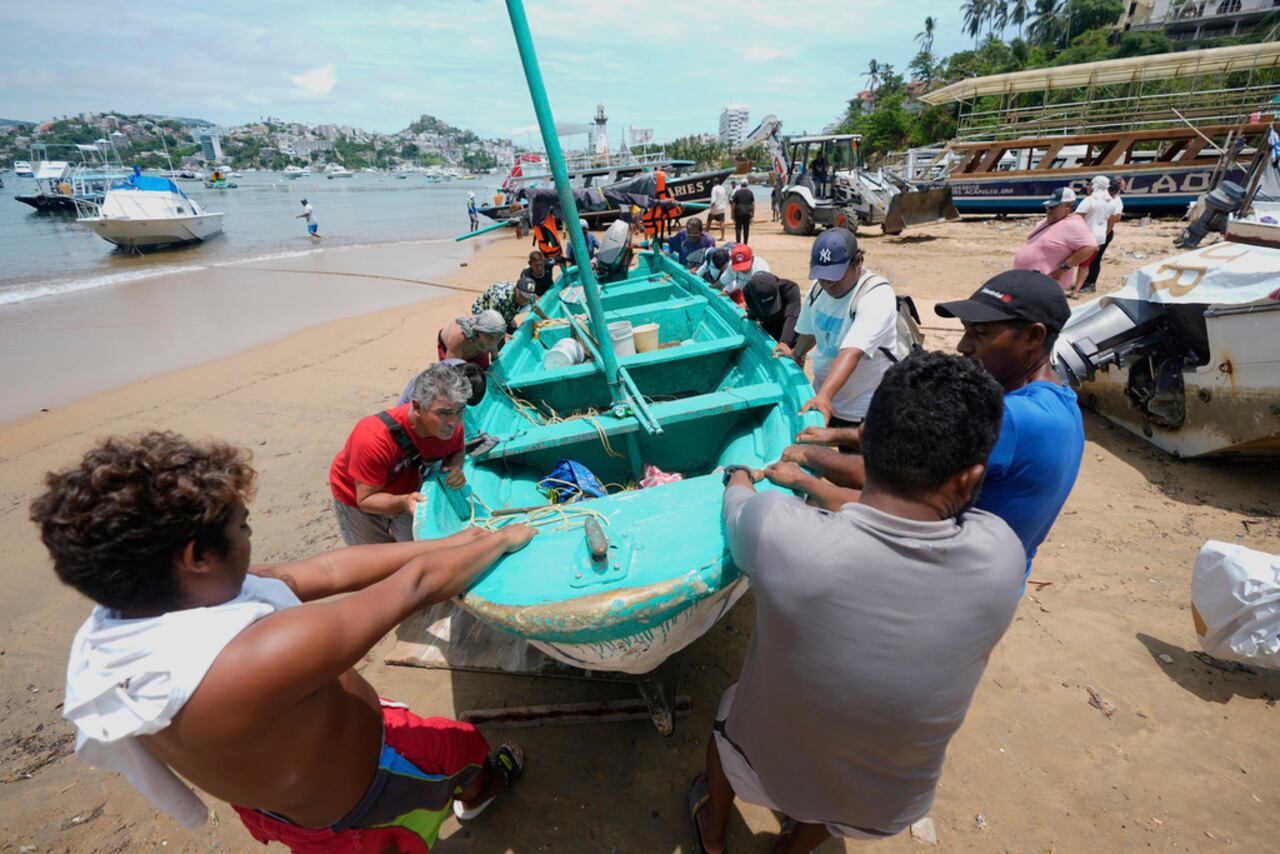 Un grupo de personas retirando del agua una embarcación en la playa de Manzanillo antes de la llegada del huracán Erick en Acapulco, México, el miércoles 18 de junio de 2025. (AP Foto/Fernando Llano)
