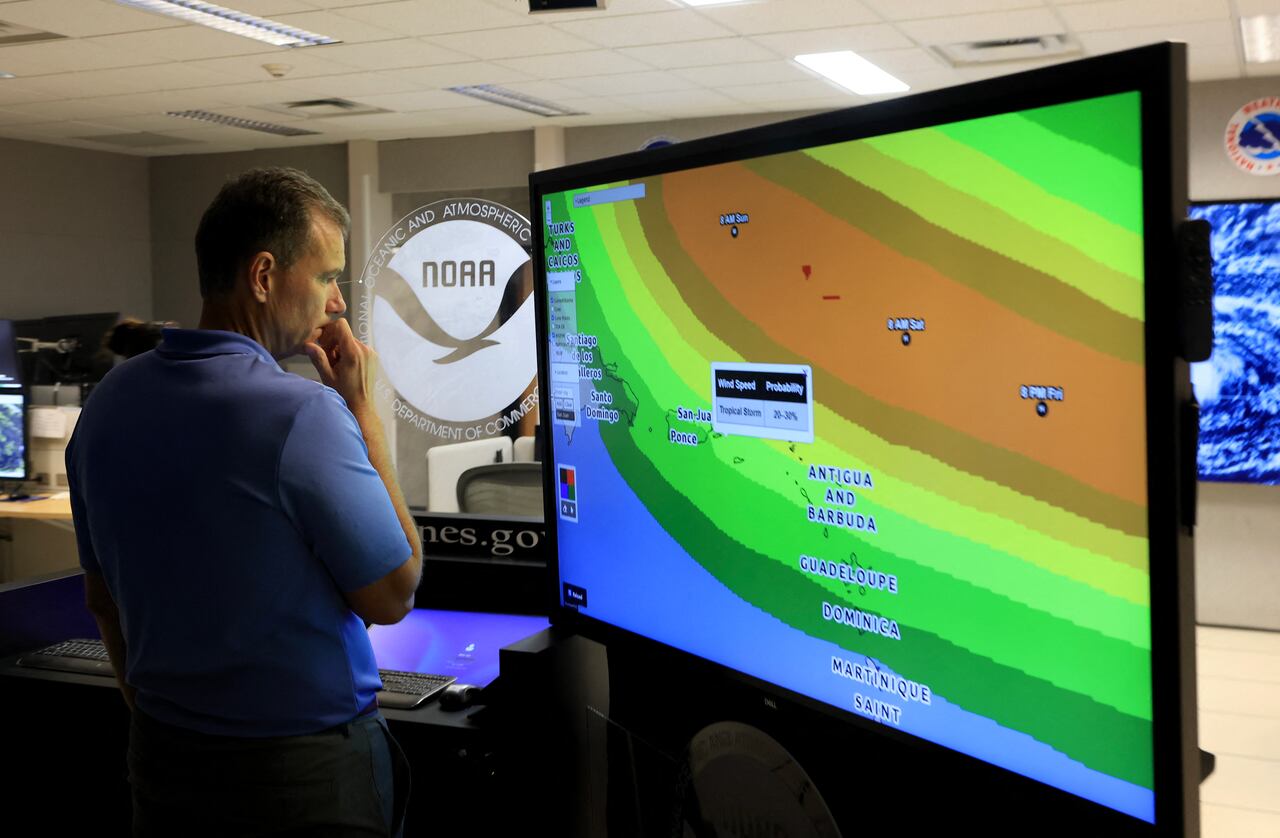 MIAMI, FLORIDA - 13 DE AGOSTO: Jamie Rhome, subdirector del Centro Nacional de Huracanes, observa una pantalla que muestra las trayectorias que podría tomar la tormenta tropical Erin mientras se sigue su avance en el Centro Nacional de Huracanes el 13 de agosto de 2025 en Miami, Florida. El Centro Nacional de Huracanes indica que Erin tiene el potencial de convertirse en el primer gran huracán de la temporada 2025. Joe Raedle/Getty Images/AFP (Foto de JOE RAEDLE / GETTY IMAGES NORTH AMERICA / Getty Images vía AFP)