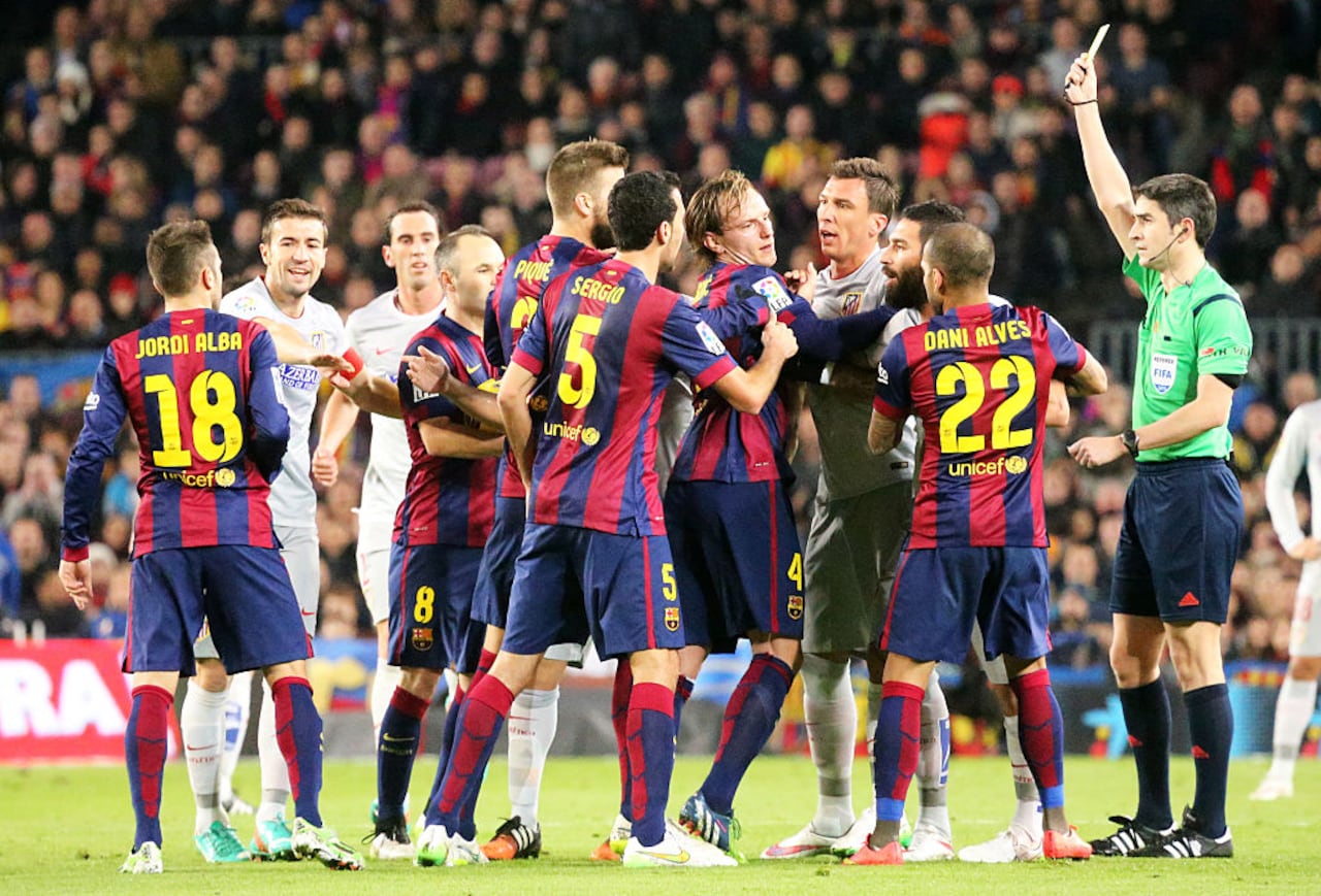 BARCELONA - 11 de enero - ESPAÑA: Enfrentamiento entre jugadores y el árbitro Alberto Undiano Mallenco muestra tarjeta amarilla en el partido entre el FC Barcelona y el Atlético de Madrid, correspondiente a la jornada 18 de la Liga española BBVA, disputado en el Camp Nou, el 11 de enero de 2014. (Foto de NurPhoto/NurPhoto a través de Getty Images)