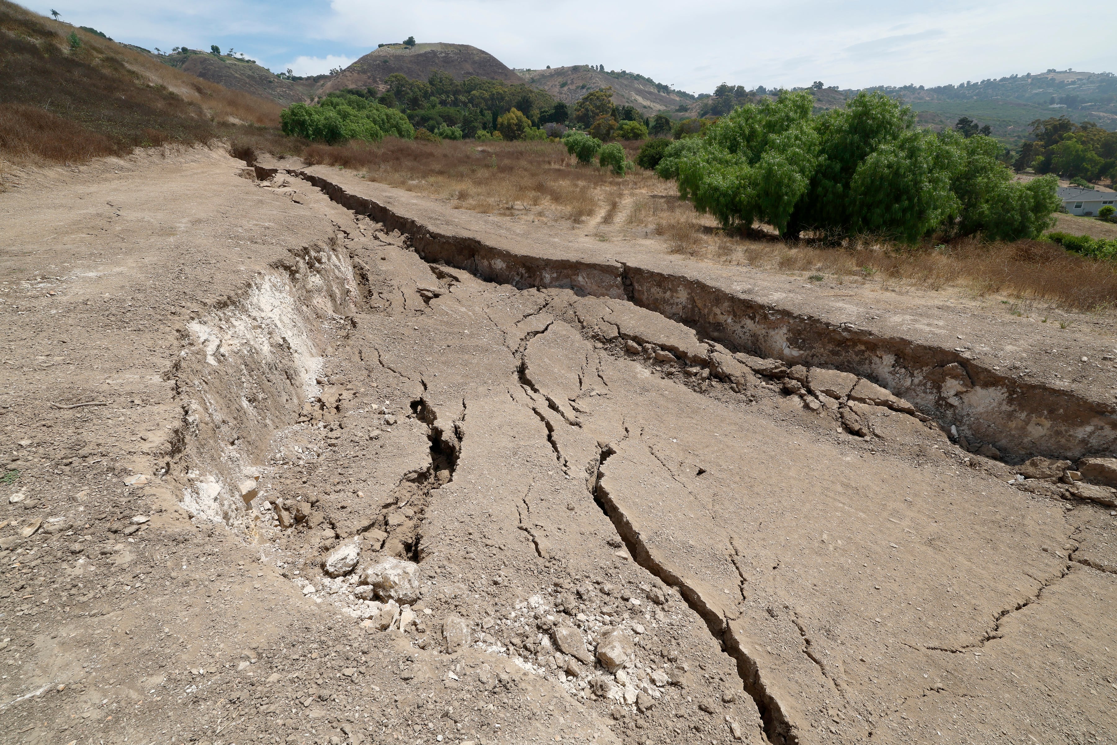 Rancho Palos Verdes, CA - 1 de agosto: Una vista de una gran fisura que se abrió desde febrero, dañando una casa de Portuguese Bend después de las fuertes lluvias del invierno pasado en Rancho Palos Verdes el jueves 1 de agosto de 2024. Debido al continuo movimiento de tierra, El vecindario de Portuguese Bend en Rancho Palos Verde podría enfrentar un corte de energía. Mike Hong, cuya casa está al lado de una gran fisura que se ha ido haciendo más grande y profunda desde febrero, cuando la zona quedó inundada por fuertes lluvias. Dice que el agua drena desde las casas de Rolling Hills hacia el Cañón de Altamira y fluye directamente hacia la tierra y no hacia el océano, lo cual es parte de un plan de drenaje propuesto. Dice que revestir el cañón ayudaría, ya que la saturación de lluvia es uno de los factores que contribuyen al movimiento en el área.