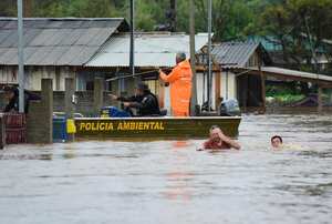 Agentes de policía revisan una casa mientras habitantes vadean una calle inundada por tormentas derivadas de un ciclón en Passo Fundo, en el estado de Rio Grande do Sul, Brasil, el lunes 4 de septiembre de 2023. (AP Foto/Diogo Zanatta-Futura Press)