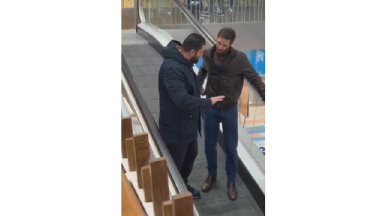 Joven ayuda a un hombre con miedo de utilizar unas escaleras eléctricas