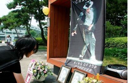 Una joven deposita flores junto a varios ramos, velas, fotos y cartas de fans para conmemorar el primer aniversario de la muerte del cantante estadounidense Michael Jackson en el estadio Jamsil de Seúl, Corea del Sur.