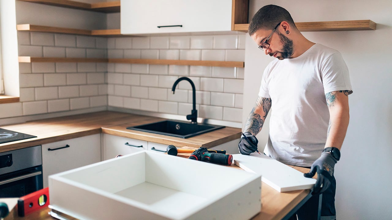 The focused carpenter marks with a pencil where he will cut the wooden material he needs during the renovation of the kitchen.