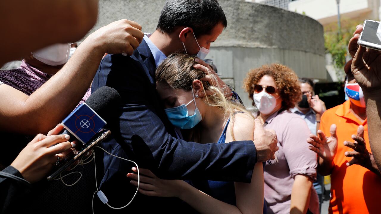 El líder opositor Juan Guaidó y su esposa, Fabiana Rosales, se abrazan en el estacionamiento de su edificio residencial mientras sostienen una conferencia de prensa improvisada en Caracas, Venezuela, el lunes 12 de julio de 2021. Guaidó dijo que las fuerzas de seguridad amenazaron a su conductor cuando él y su conductor llegaron casa el lunes. (Foto AP / Ariana Cubillos)