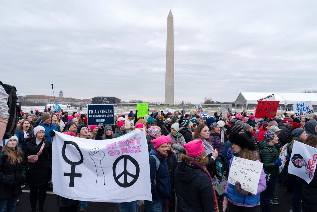 Con el Monumento a Washington al fondo, los manifestantes sostienen sus carteles mientras protestan contra la administración entrante del presidente electo Donald Trump durante la Marcha Popular, el sábado 18 de enero de 2025, en Washington. (Foto AP/José Luis Magaña)