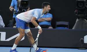 Novak Djokovic of Serbia stretches his injured leg during his fourth round match against Alex de Minaur of Australia at the Australian Open tennis championship in Melbourne, Australia, Monday, Jan. 23, 2023. (AP Photo/Aaron Favila)