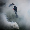 Un manifestante se para en nubes de gases lacrimógenos en medio de enfrentamientos con la policía antidisturbios durante una manifestación el Primero de Mayo (Día del Trabajo), para conmemorar el día internacional de los trabajadores, más de un mes después de que el gobierno aprobara una impopular ley de reforma de las pensiones en el parlamento, en Nantes. , noroeste de Francia, el 1 de mayo de 2023. - Los partidos de oposición y los sindicatos han instado a los manifestantes a mantener su campaña de tres meses contra la ley que aumentará la edad de jubilación de 62 a 64. (Foto de LOIC VENANCE / AFP)