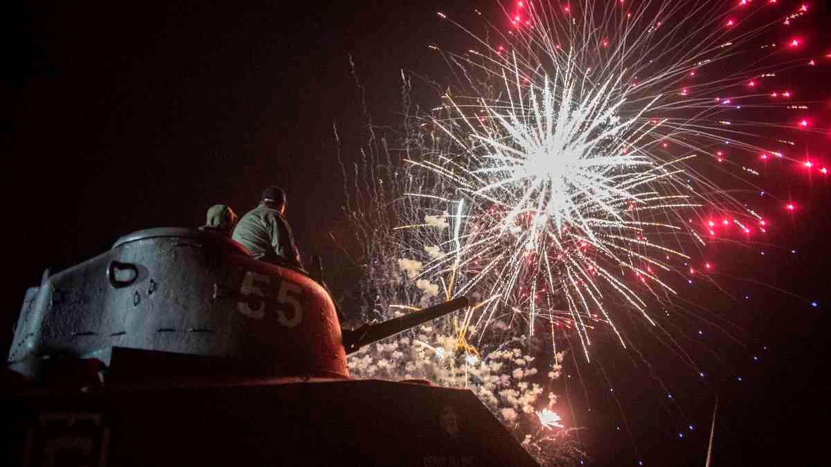 6 de junio - Espectadores sentados en un tanque de guerra ven los fuegos artificiales en Arromanches, Francia, al cierre de la celebración. Fotógrafo: Rafael Yaghobzadeh / AP