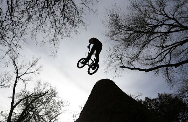 Un ciclista vuela a través de los árboles mientras salta de un montículo en el parque de Austin, Texas. (AP)