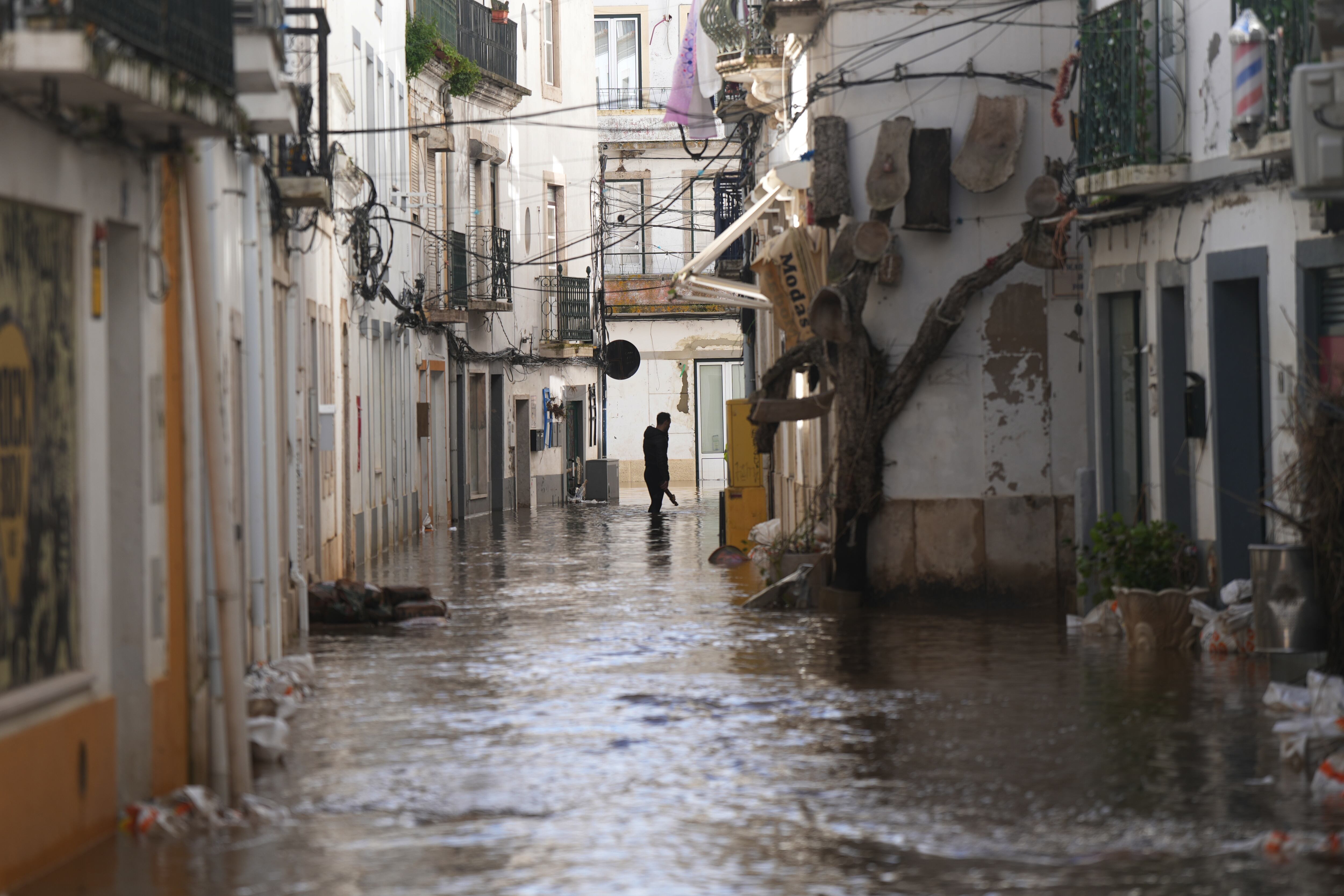 Un residente camina por una calle inundada tras el desbordamiento del río Sado tras las fuertes lluvias en Alcácer do Sal, en el sur de Portugal.