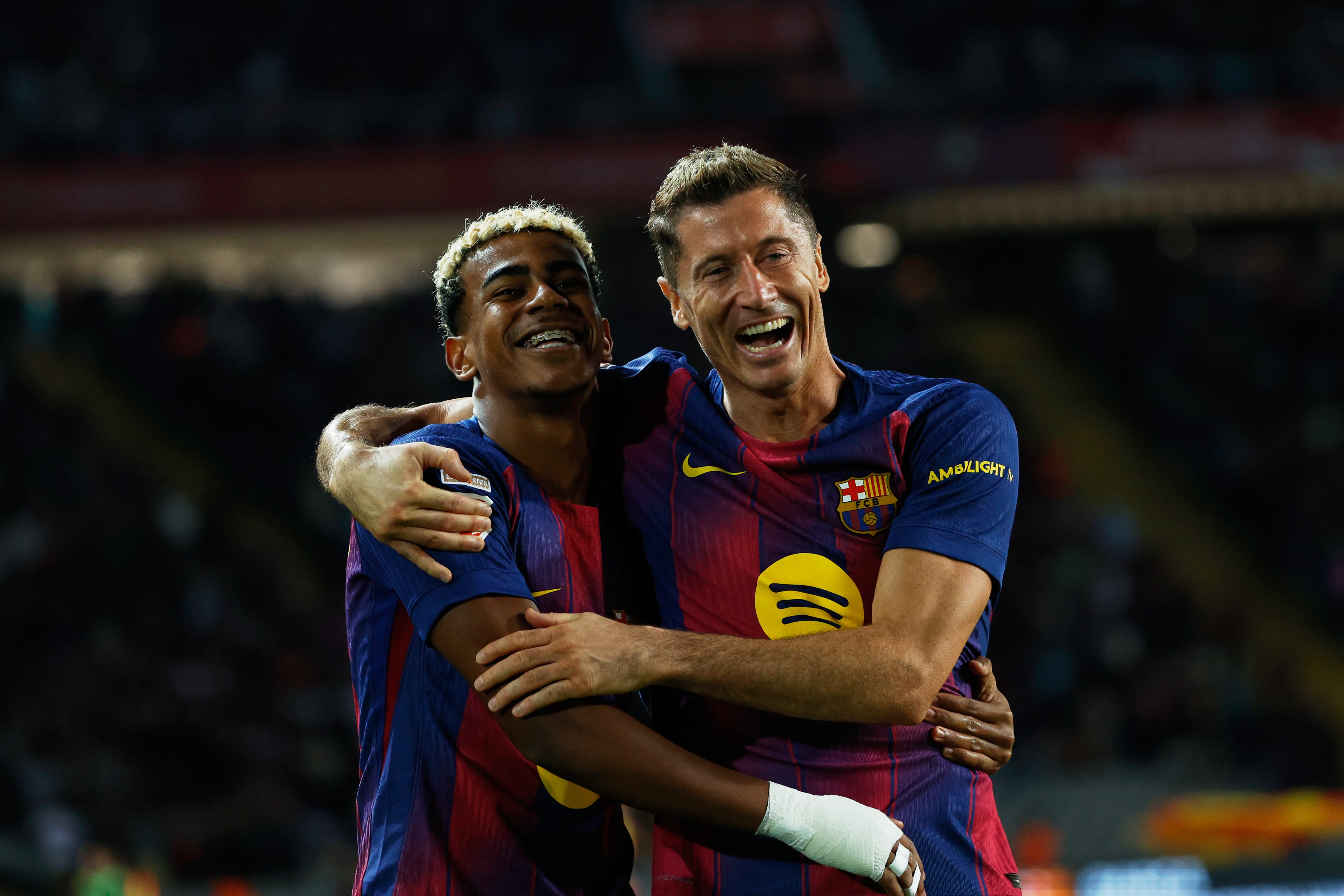 Robert Lewandowski (derecha) del Barcelona celebra con Lamine Yamal el segundo gol de su equipo en la victoria 2-1 ante la Real Sociedad en el Estadio Olímpico Lluís Companys en Barcelona, el domingo 28 de septiembre de 2025. (AP Foto/Joan Monfort)