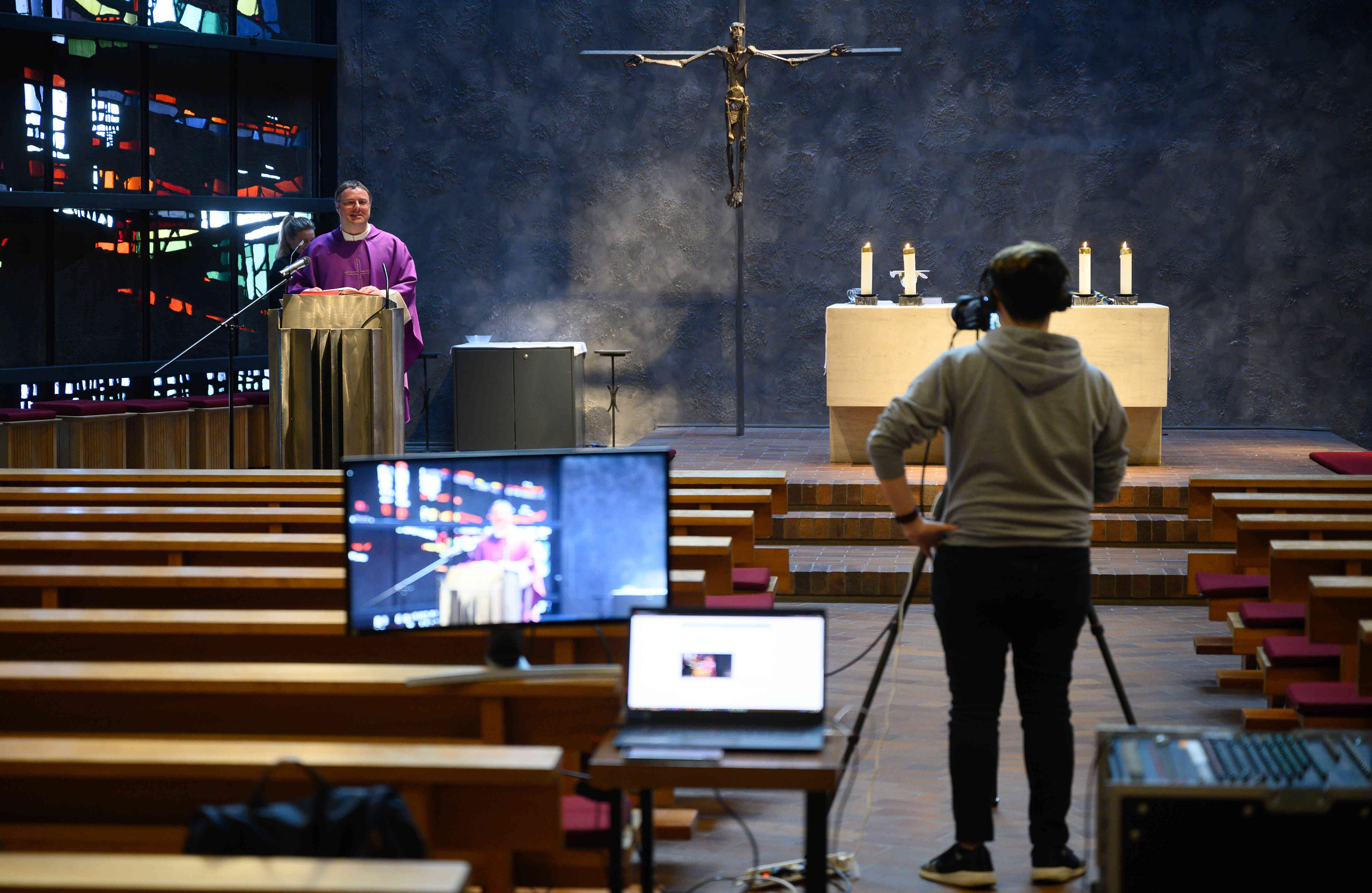 El sacerdote Patrick Stauss realiza misa en una iglesia vacía. La ceremenonia es filmada y transmitida por un operador de cámara en Youtube a la comunidad en Winterbach, sur de Alemania, el 22 de marzo de 2020. Foto: Sebastian Gollnow / dpa / AFP