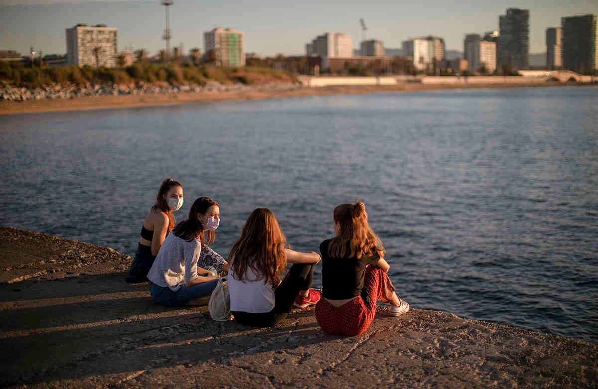 Un grupo de mujeres con mascarillas se sientan frente al mar en Barcelona, España, el miércoles 20 de mayo de 2020. Barcelona permitió el miércoles que las personas caminen por sus playas para primera vez desde el inicio del bloqueo de virus hace más de dos meses. (Foto AP / Emilio Morenatti)